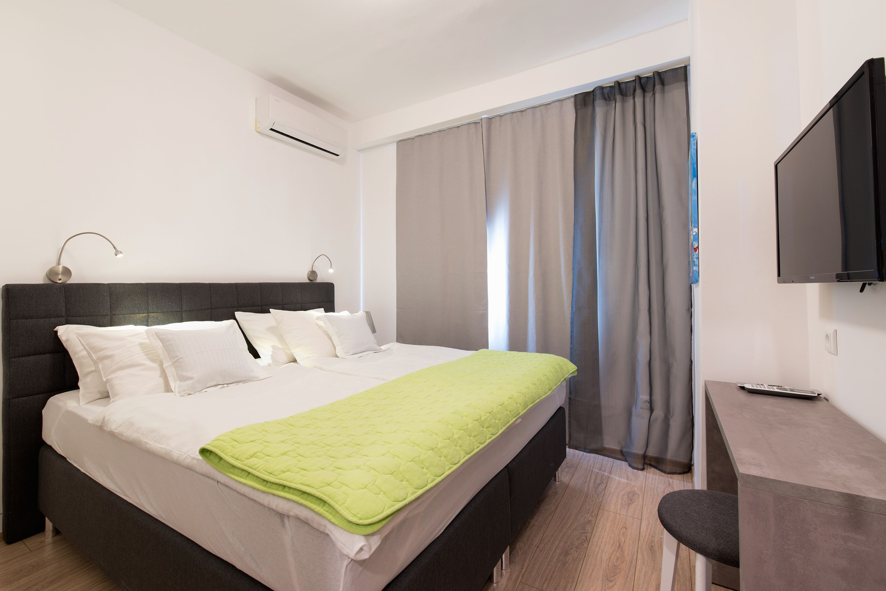 Una habitación de hotel moderna con una cama grande, un escritorio y un televisor de pantalla plana.