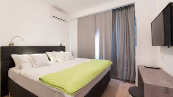 Una habitación de hotel moderna con una cama grande, un escritorio y un televisor de pantalla plana.