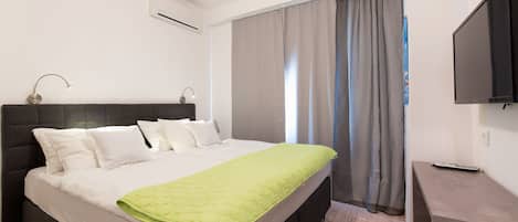 A modern hotel room with a large bed, a desk, and a flat-screen TV.
