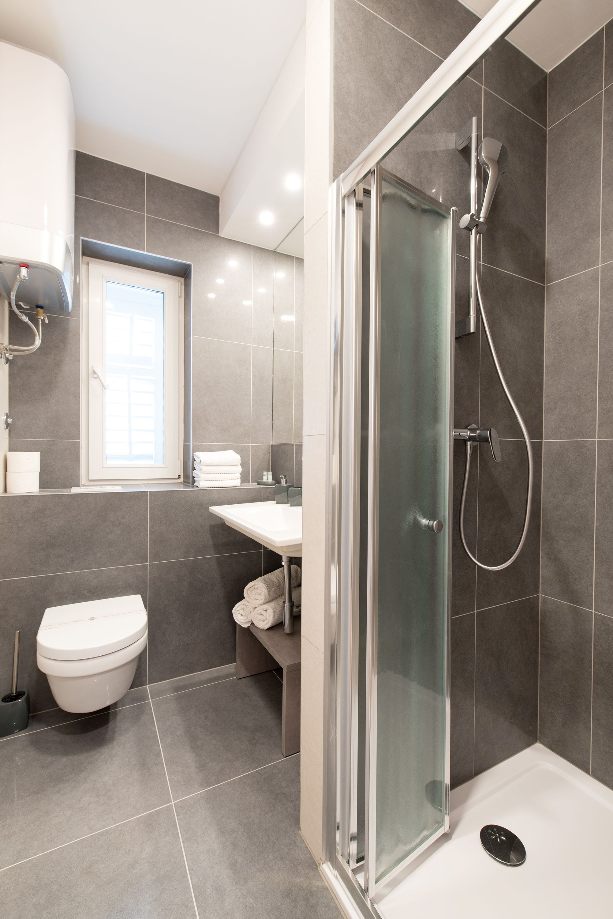 A modern bathroom with a shower, toilet, and sink.