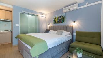 A bedroom with a bed, bedside table, and a green sofa.