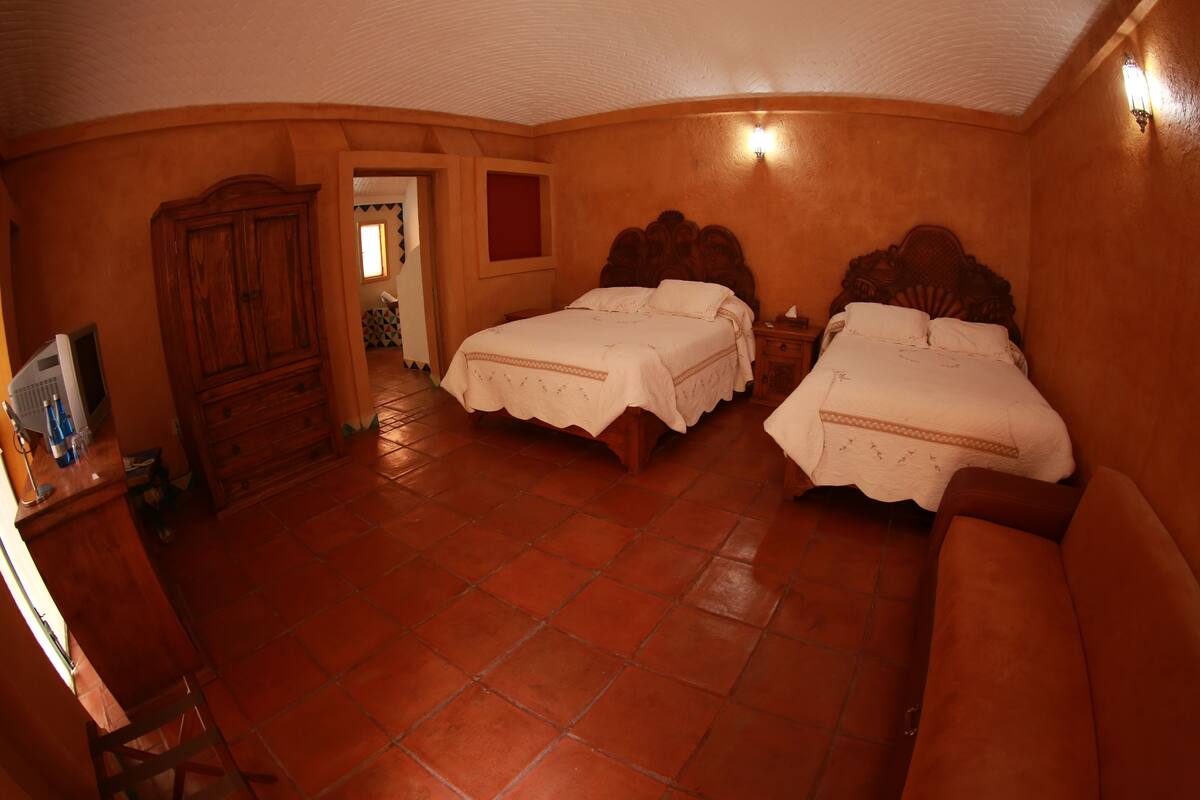 A room with two beds, a wooden wardrobe, a tiled floor, and a small desk with a computer.