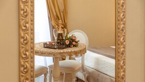Una habitación con una cama, una mesa con mantel de encaje, una botella de champán, dos copas y un ramo de flores.