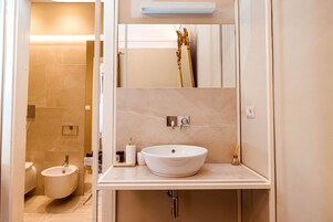 Un bagno moderno con un lavandino bianco grande, un bidet e uno specchio sopra il lavandino.
