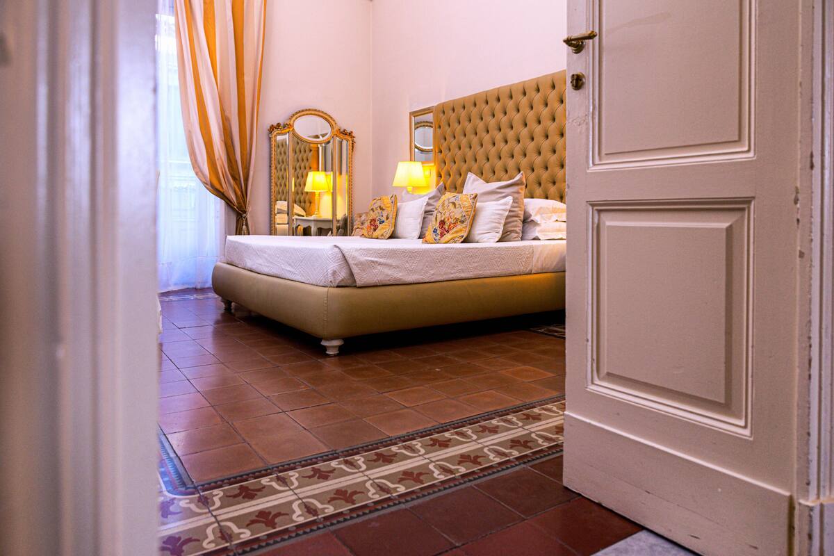 A hotel room with a bed, a mirror, and a door.