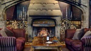 A cozy room with a stone fireplace, two upholstered sofas, a wooden coffee table, and a book. - Mitton Hall Country House Hotel (Clitheroe)