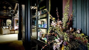 A room with a large window, a bookshelf, and a floral arrangement. - Mitton Hall Country House Hotel (Clitheroe)