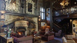 A grand room with a fireplace, ornate mirrors, and a staircase leading to an upper level. - Mitton Hall Country House Hotel (Clitheroe)