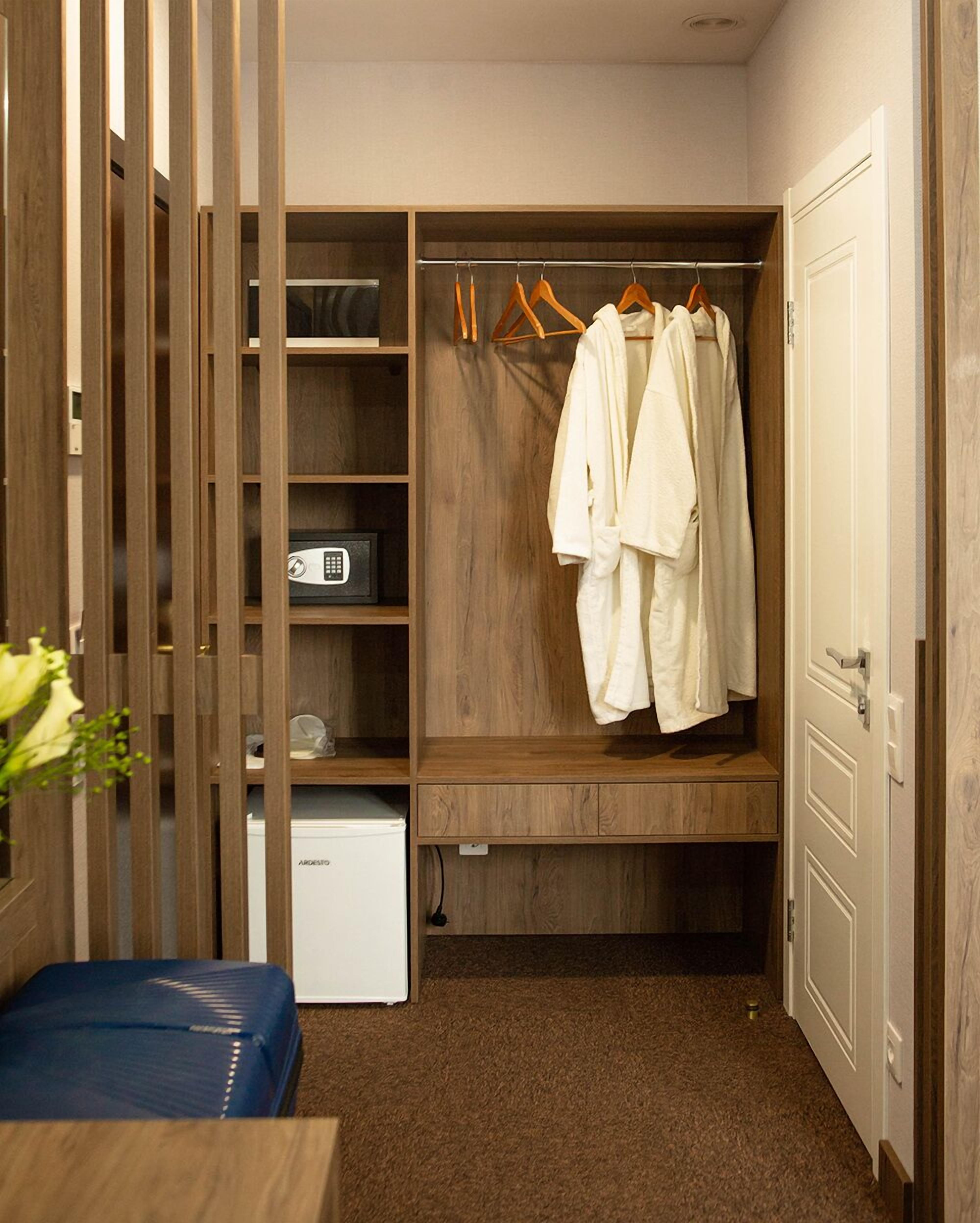 A walk-in closet with wooden shelving, a hanging rack, and a small appliance.