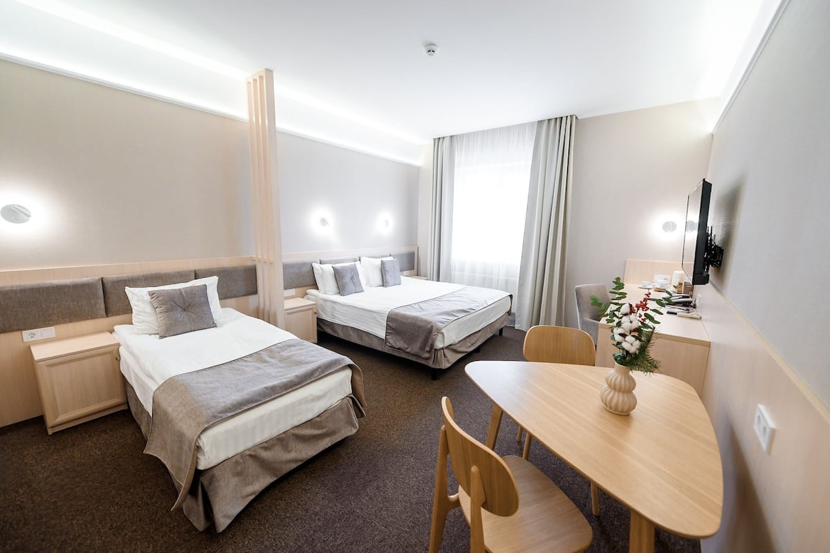 Ein Hotelzimmer mit zwei Betten, einem Schreibtisch und einem Stuhl.