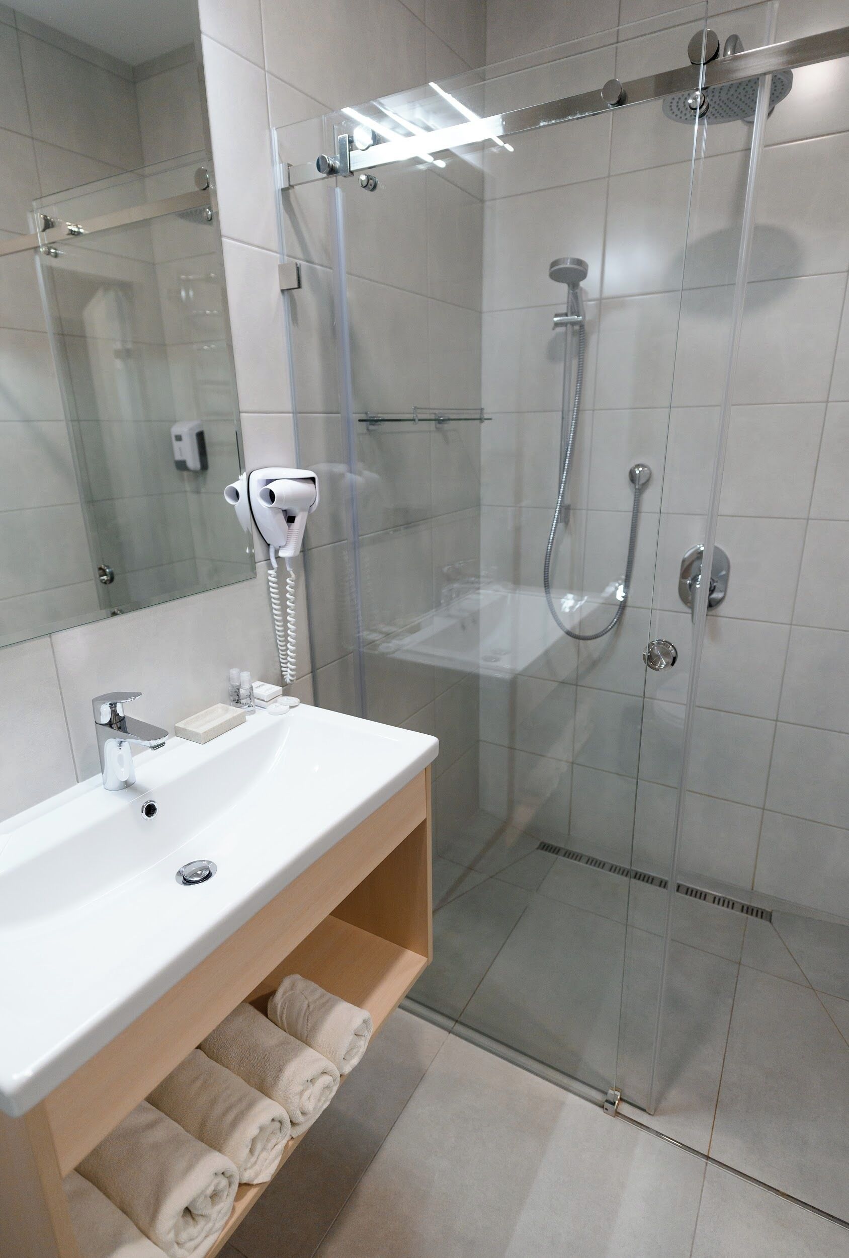 A modern bathroom with a glass-enclosed shower, a white sink, and a towel rack.