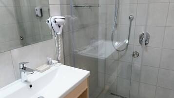 A modern bathroom with a glass-enclosed shower, a white sink, and a towel rack.