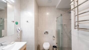 Un baño moderno con lavamanos, inodoro y cabina de ducha de vidrio.