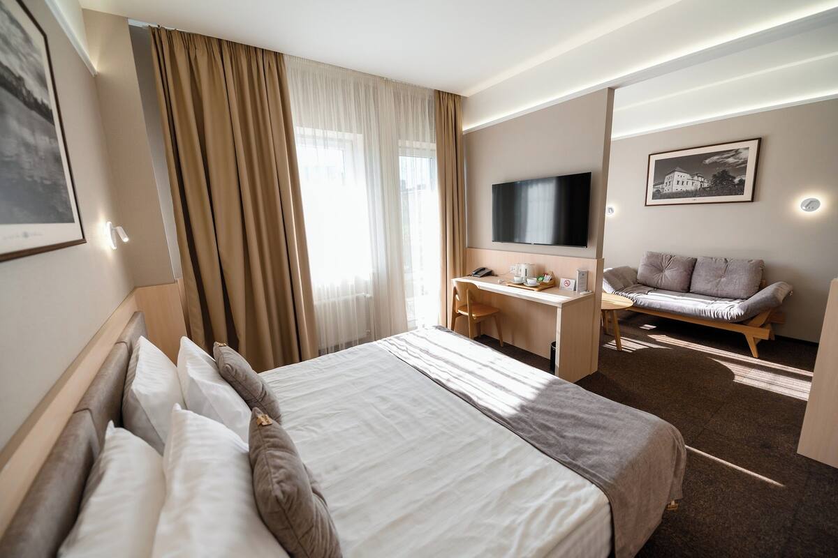 Ein Hotelzimmer mit einem großen Bett, einem Schreibtisch, einem Fernseher und einem Sofa.