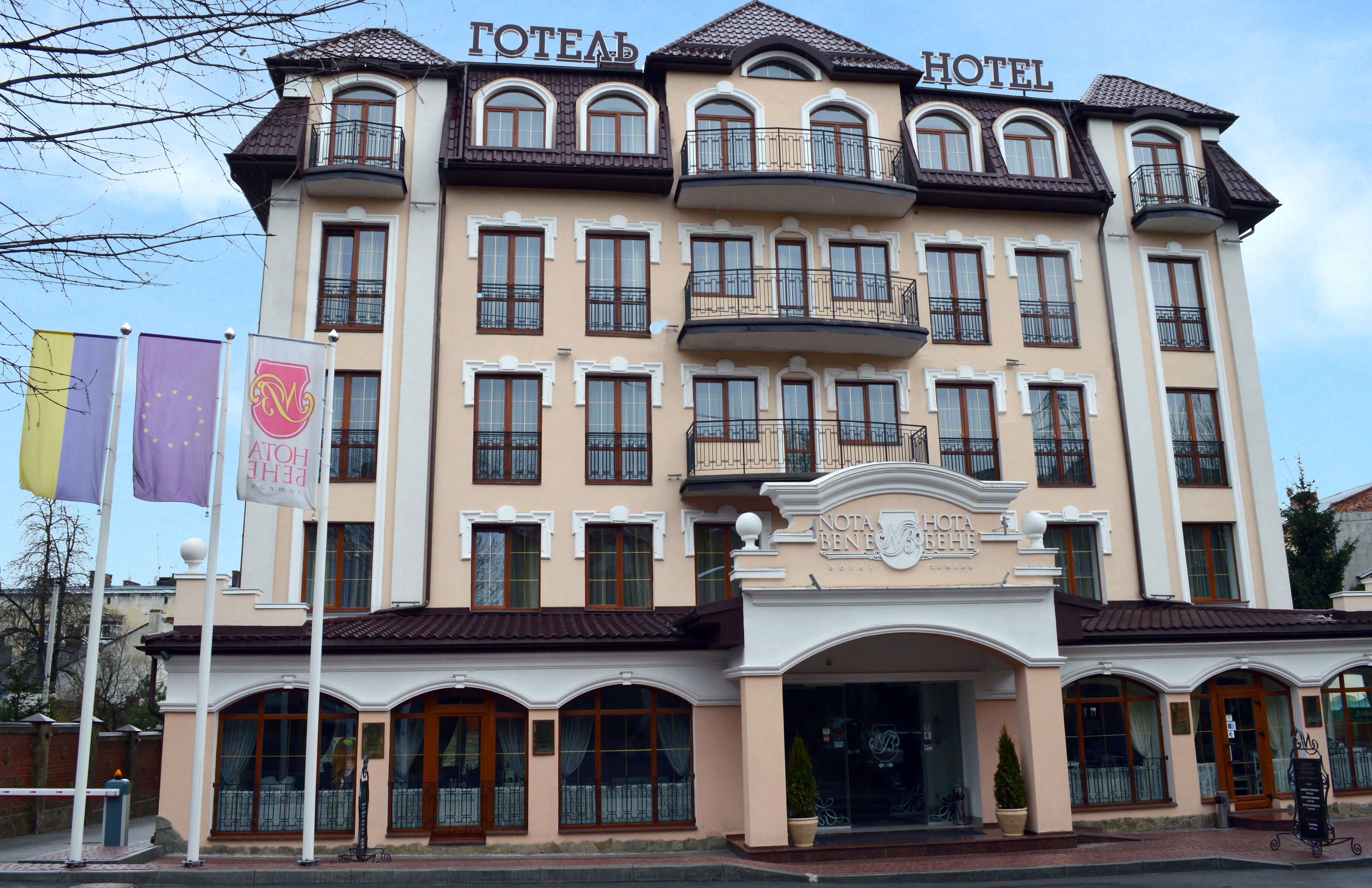 A hotel with a classic architectural style, featuring multiple balconies and a central entrance with a sign.