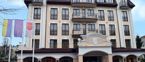 A hotel with a classic architectural style, featuring multiple balconies and a central entrance with a sign.
