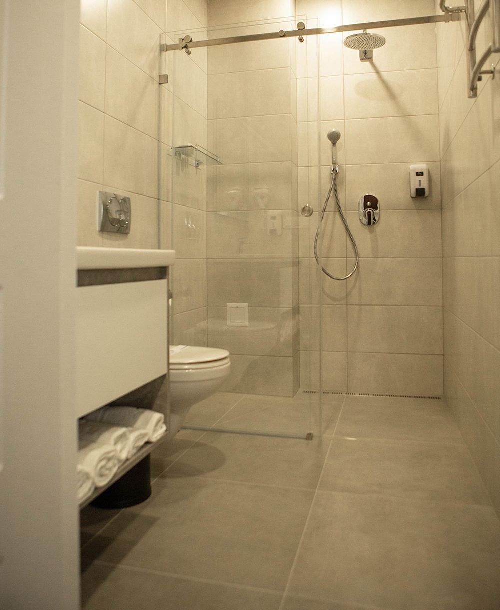 Casa de banho moderna com cabine de duche em vidro, sanita e lavatório com porta-toalhas.
