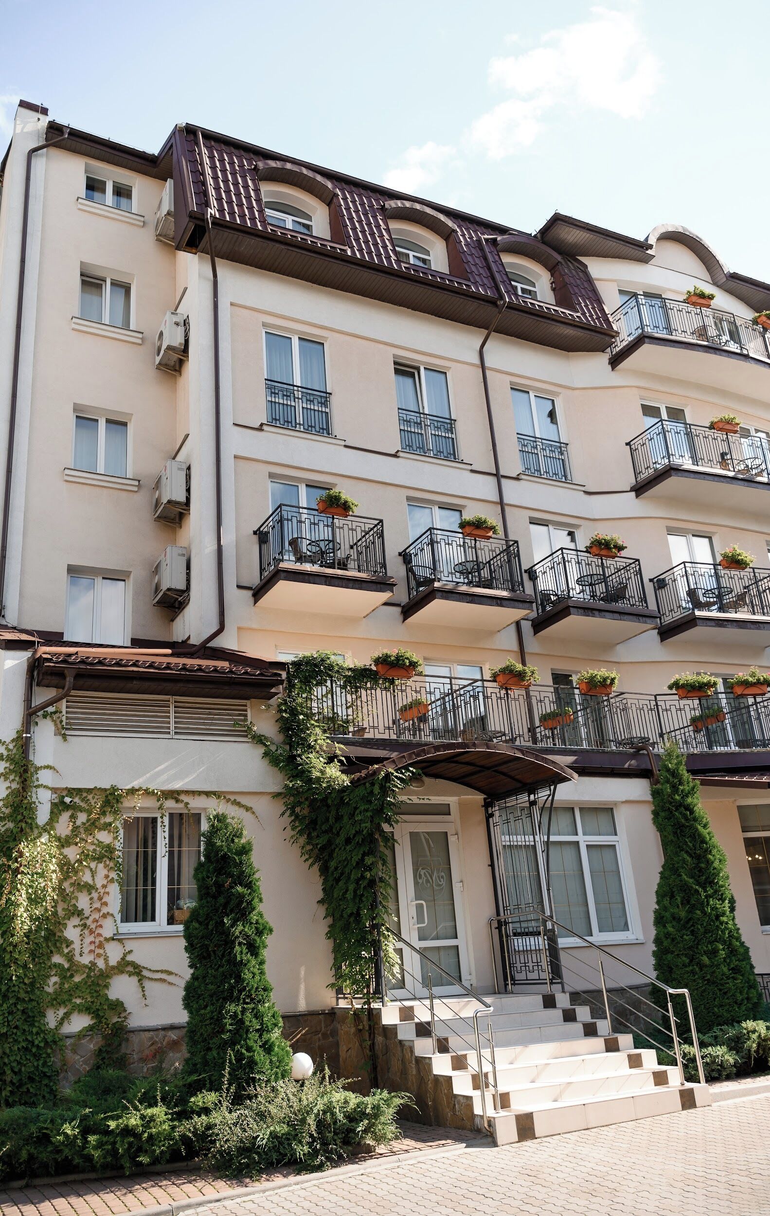 A multi-story residential building with balconies, air conditioning units, and potted plants.