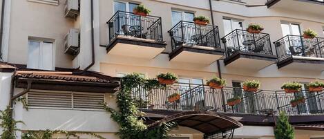 A multi-story residential building with balconies, air conditioning units, and potted plants.