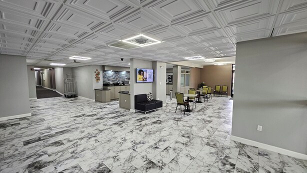 Un vestíbulo de hotel con piso de mármol, una recepción, un sofá y una zona de estar con sillas.