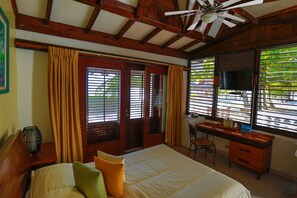 A bedroom with a bed, a desk, a chair, and a television.