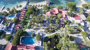An aerial view of a resort with multiple swimming pools, a beach, and a variety of buildings and palm trees. - Moulin Sur Mer (Saint-Marc)
