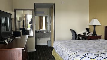 A hotel room with a bed, desk, television, and a bathroom visible through an open door.