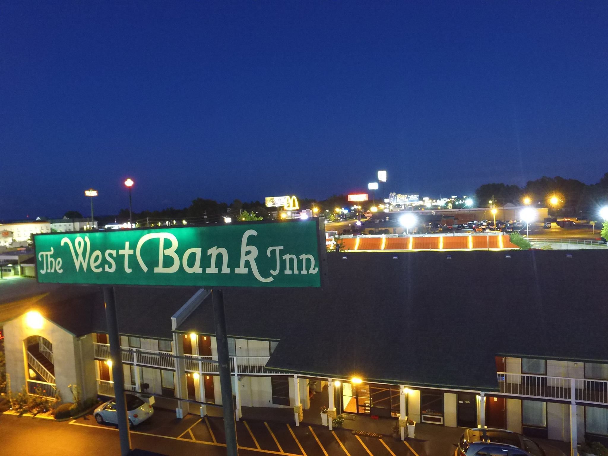 Un letrero grande del West Bank Inn, con un estacionamiento y un edificio al frente.