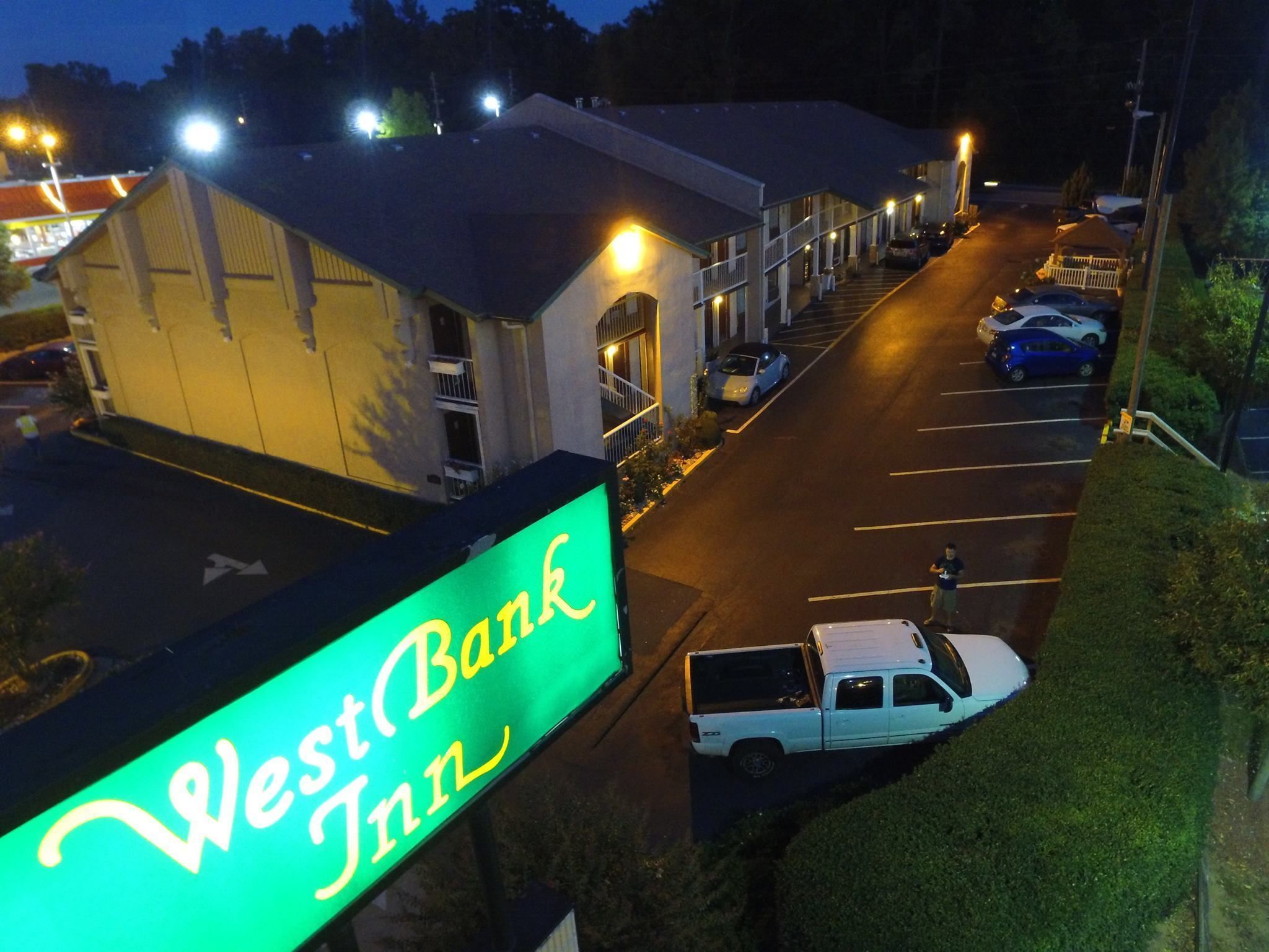 A West Bank Inn with a parking lot and a building with a sign.