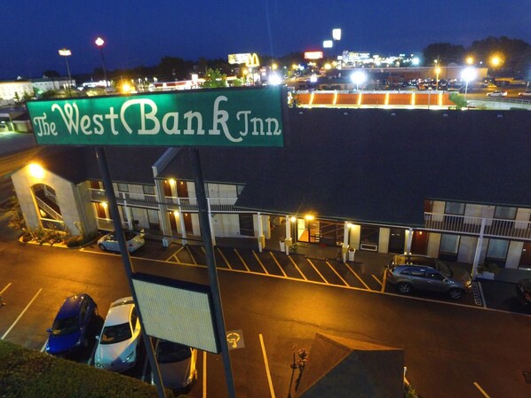 The West Bank Inn with a parking lot and a view of the surrounding area at night.