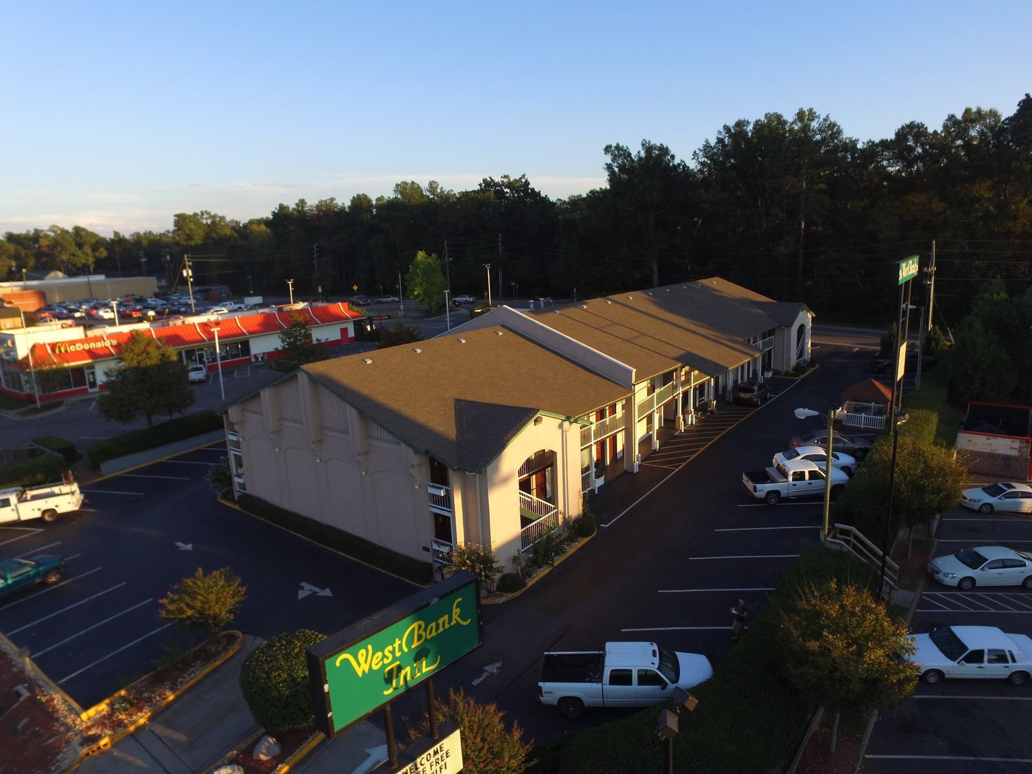 Un hôtel situé sur la rive ouest, avec un parking, un McDonald's de l'autre côté de la rue et une zone boisée en arrière-plan.