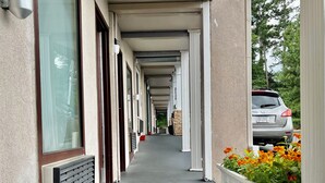 A covered walkway with a series of windows and doors, leading to a building entrance. - West Bank Inn (Augusta)