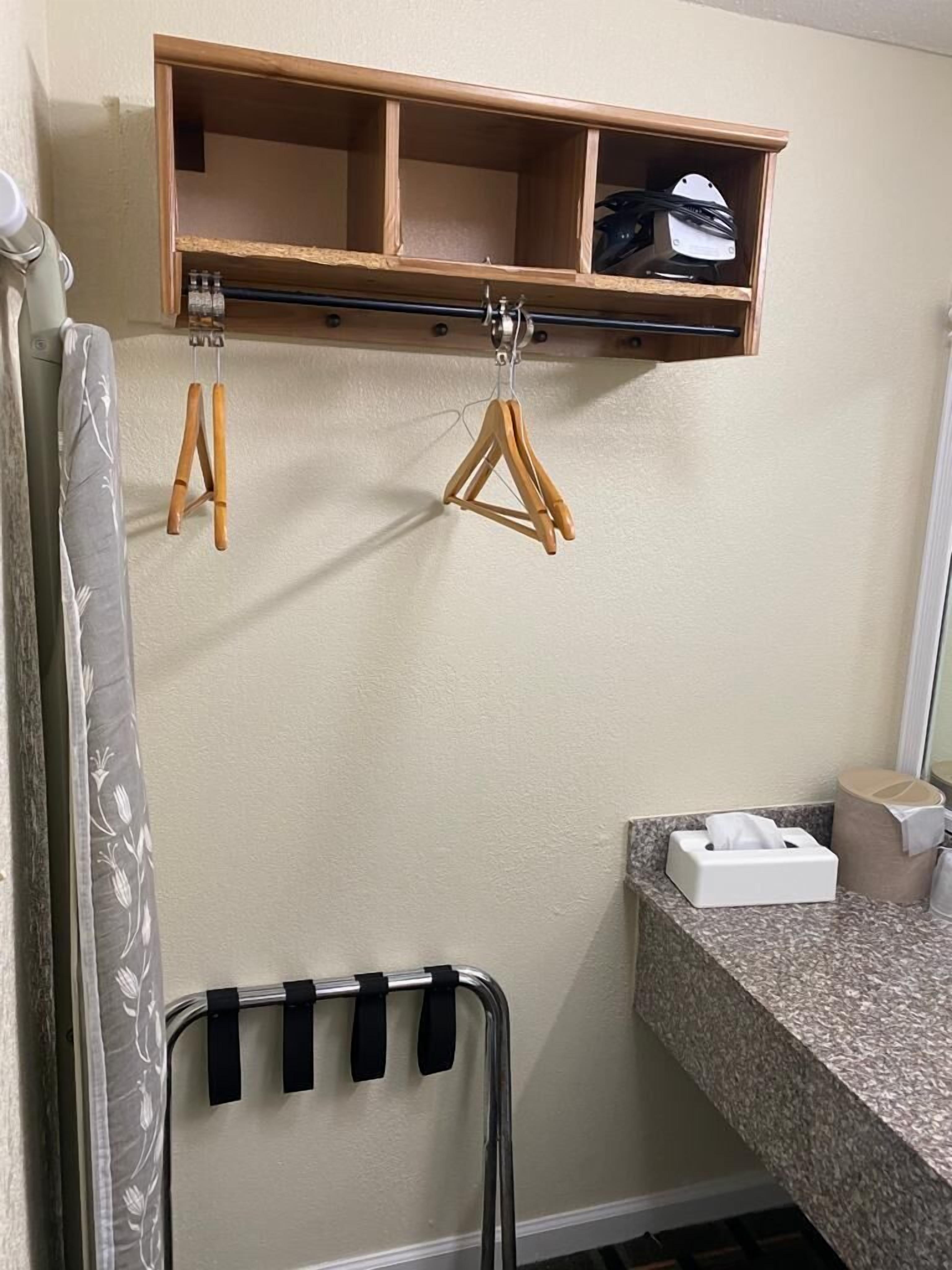 A bathroom with a wooden shelf above the mirror, a towel rack, and a tissue box on the countertop.