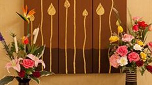 Un mostrador de recepción con un jarrón de flores, un cuenco blanco y un teléfono.