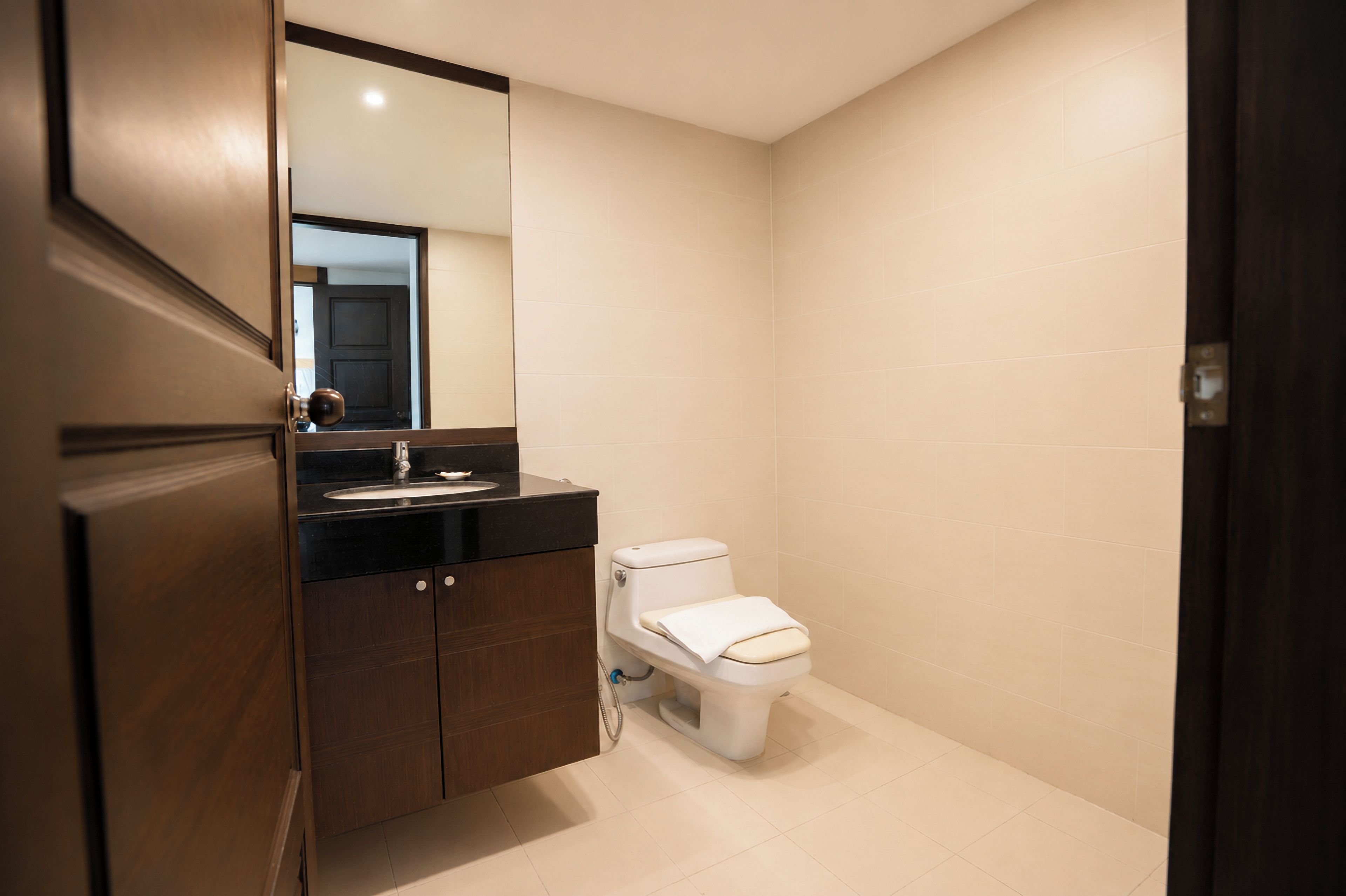 A bathroom with a toilet, sink, and mirror.