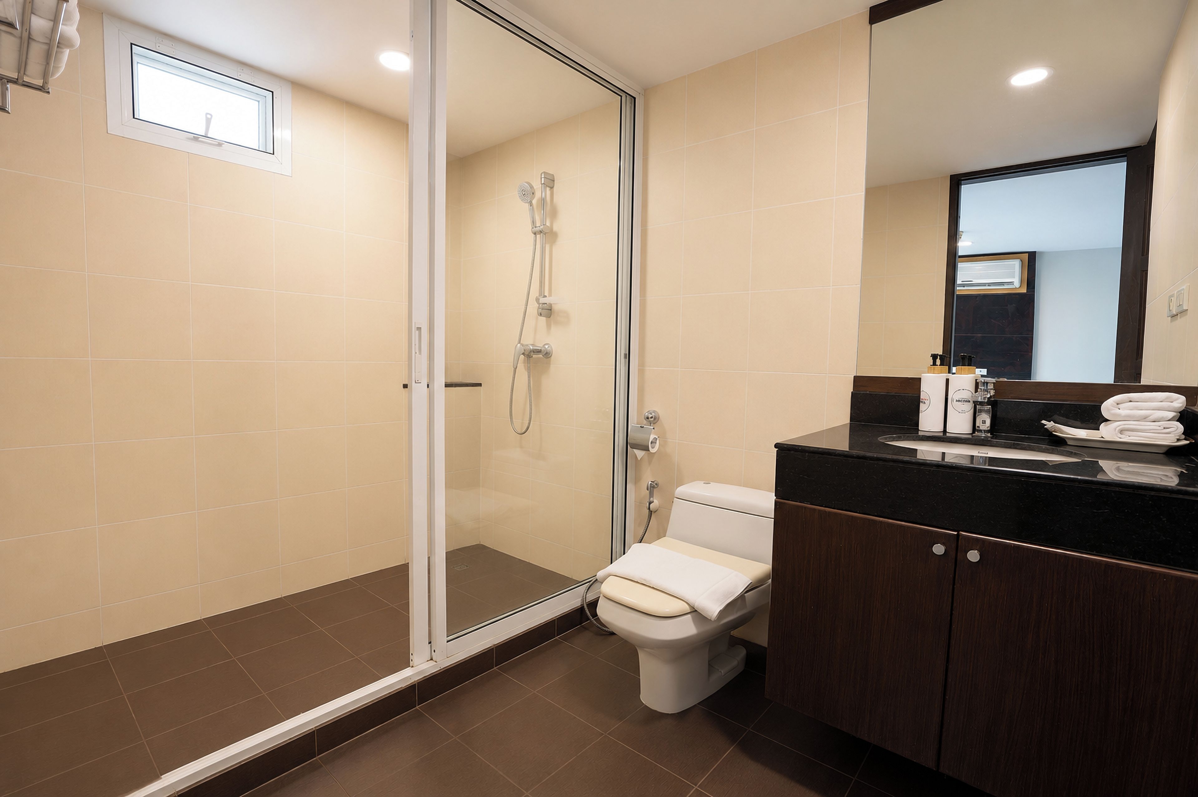 Une salle de bain moderne avec une douche à parois de verre, des toilettes et un meuble-lavabo avec un miroir.