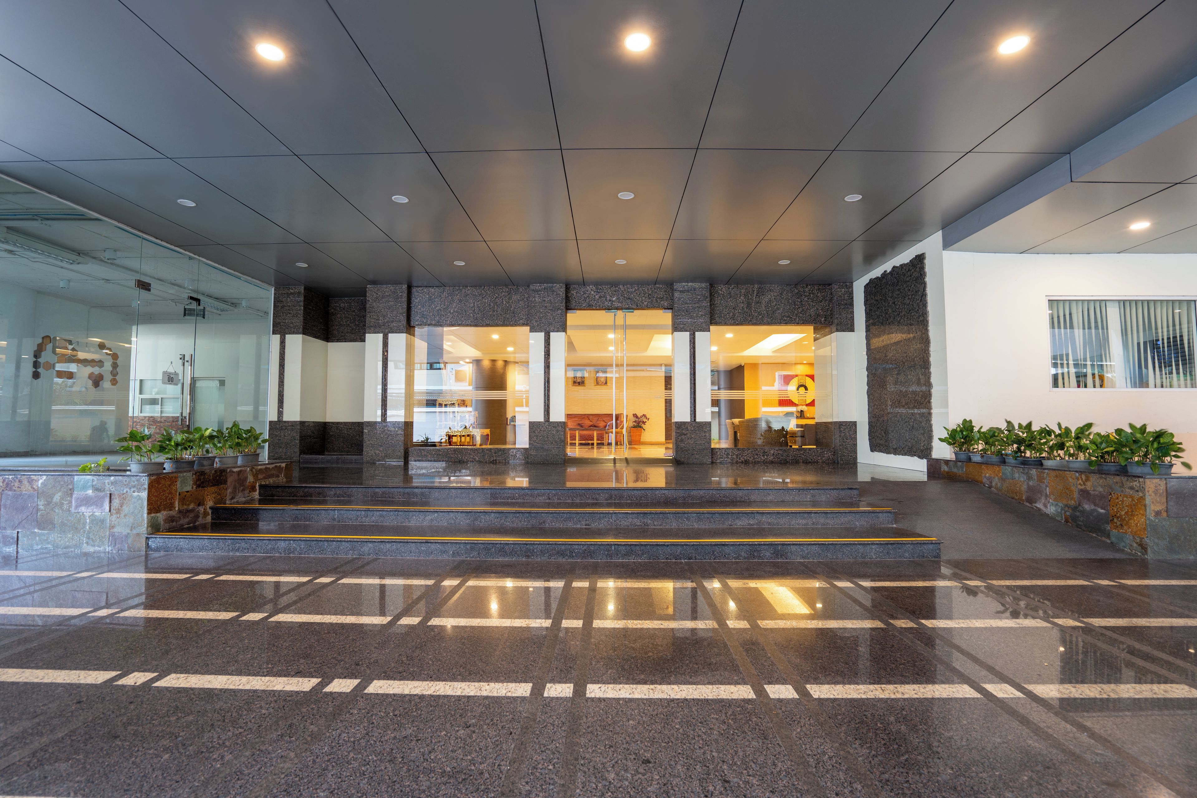 A modern hotel lobby with a marble floor, glass doors, and a reception desk.