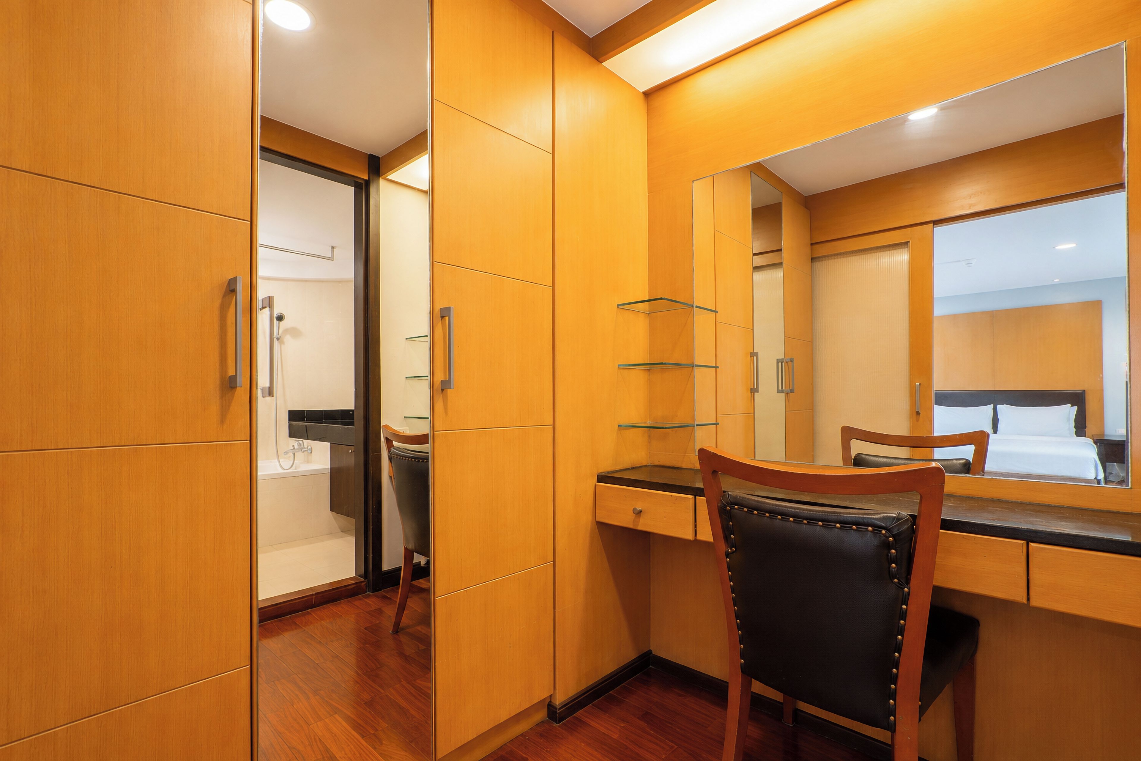Een hotelkamer met houten wanden, een bureau met stoel, een spiegel en een bed.
