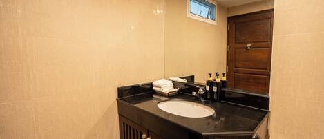 Un baño con encimera negra, lavamanos blanco y puerta de madera.
