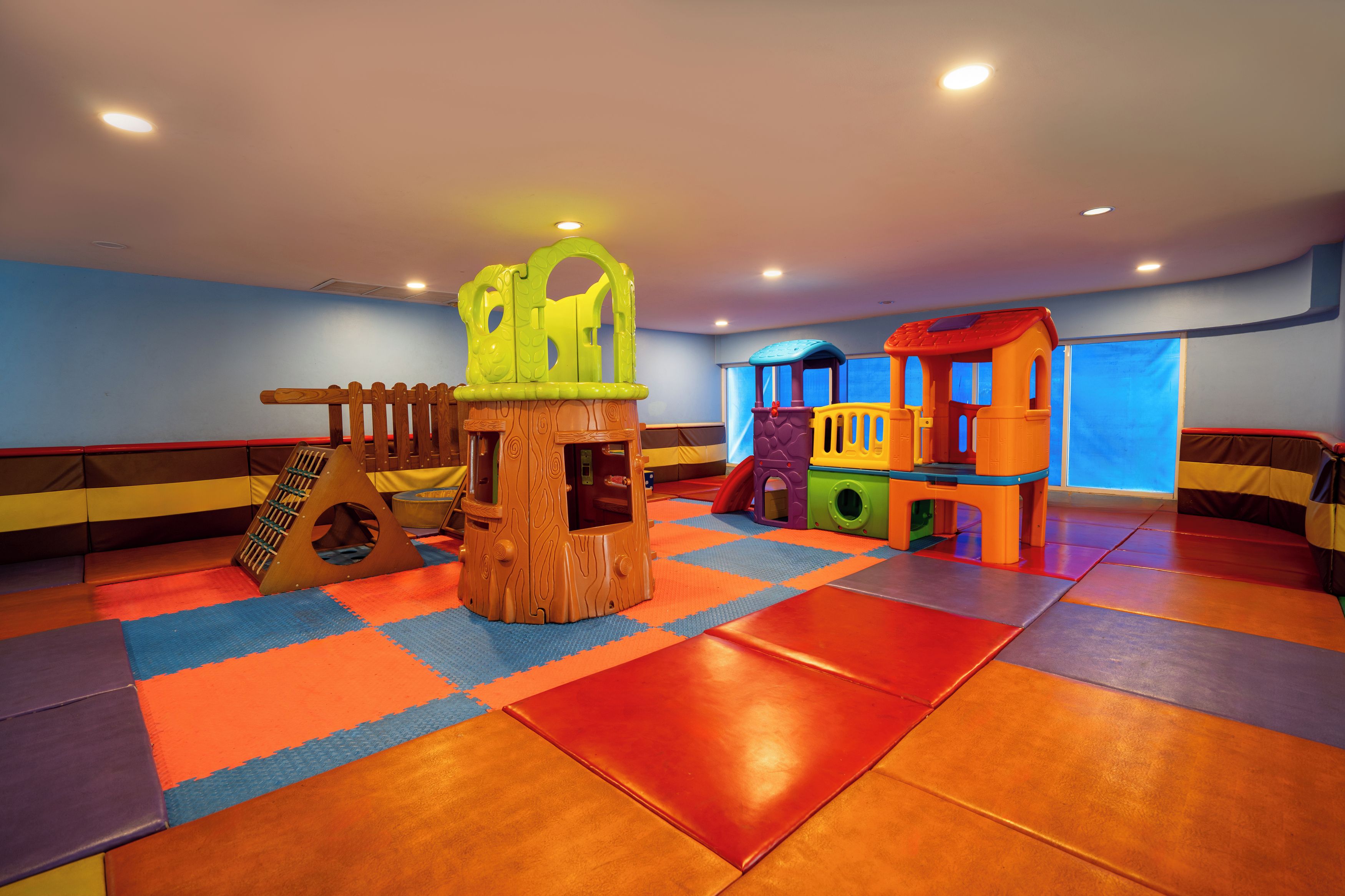 A play area with a wooden climbing structure, a slide, and a colorful playhouse.