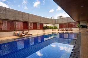 A swimming pool with lounge chairs and a tiled deck area. - The Mercer Sukhumvit 4 (Bangkok)