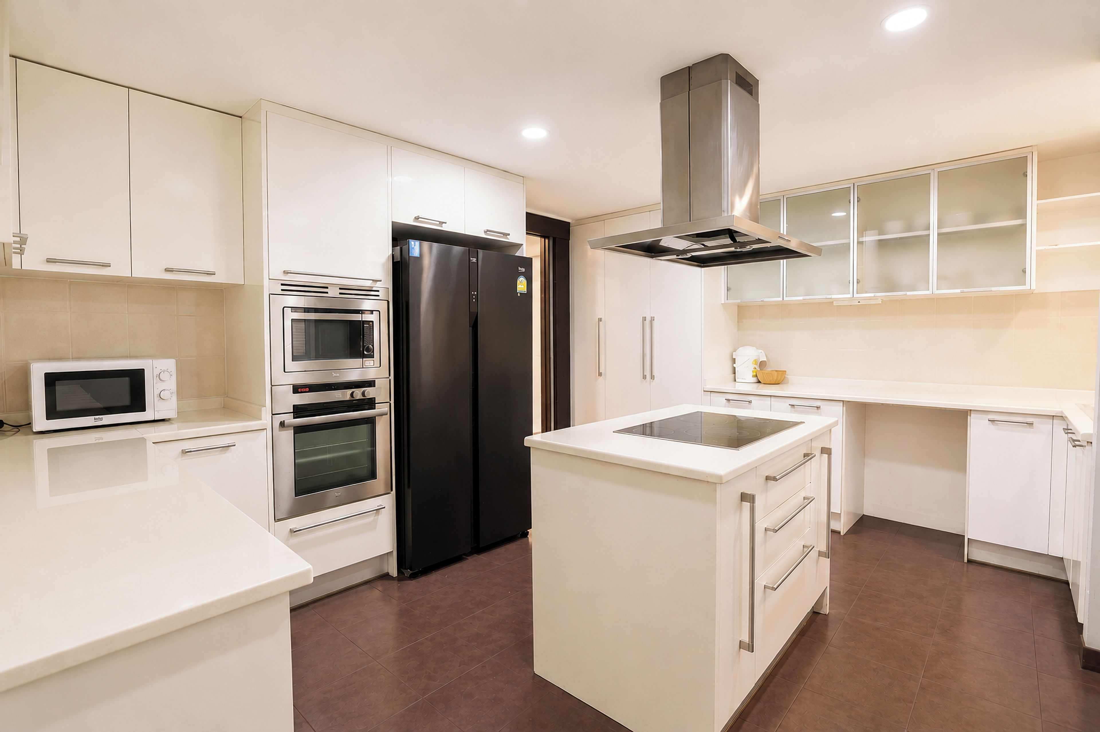 Una cocina moderna con armarios blancos, electrodomésticos de acero inoxidable y una isla central.