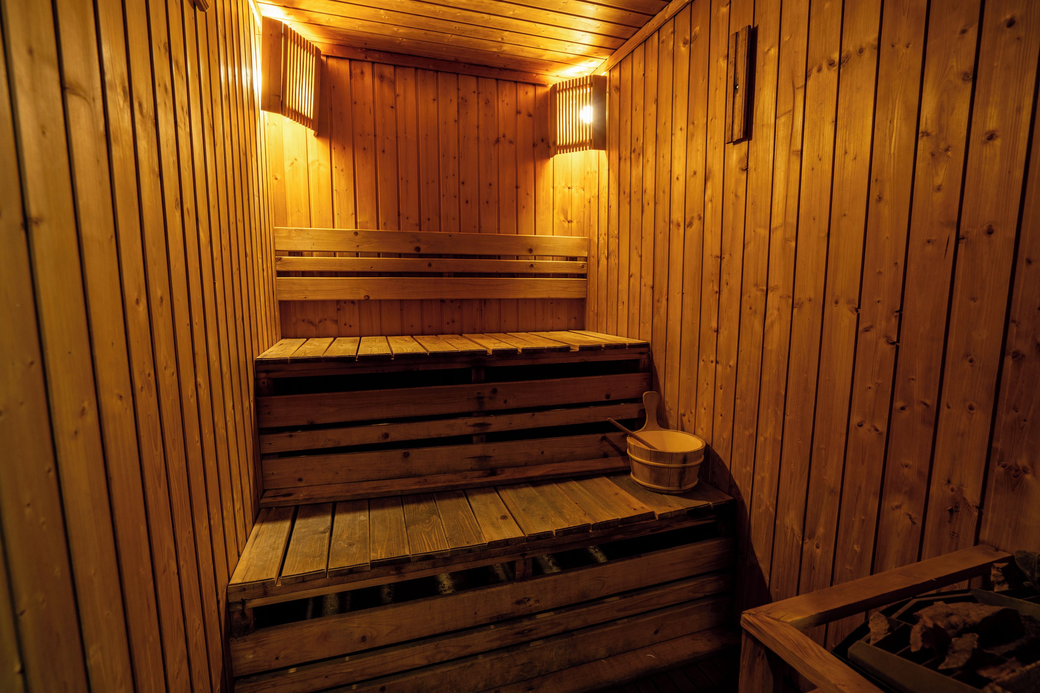 Eine Holzzimmer-Sauna mit Bänken und einem Eimer.