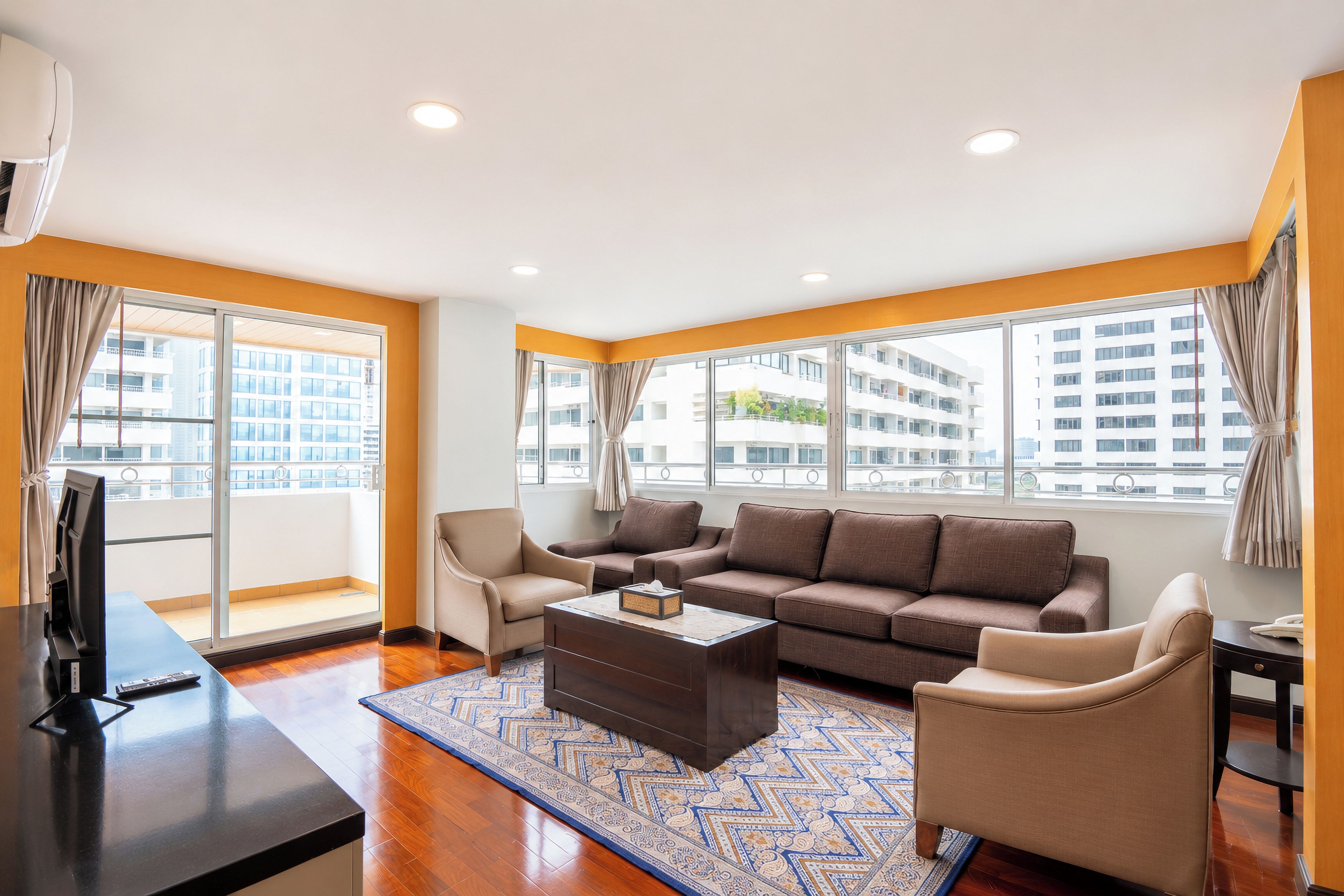 A modern living room with a sofa, armchairs, a coffee table, and a TV.