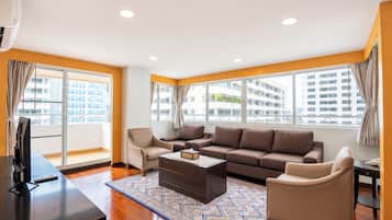 A modern living room with a sofa, armchairs, a coffee table, and a TV.
