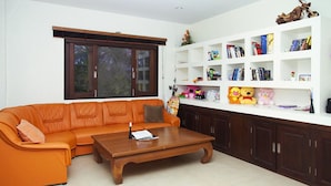 Een woonkamer met een hoekbank, een houten salontafel en een witte boekenkast vol boeken en speelgoed.