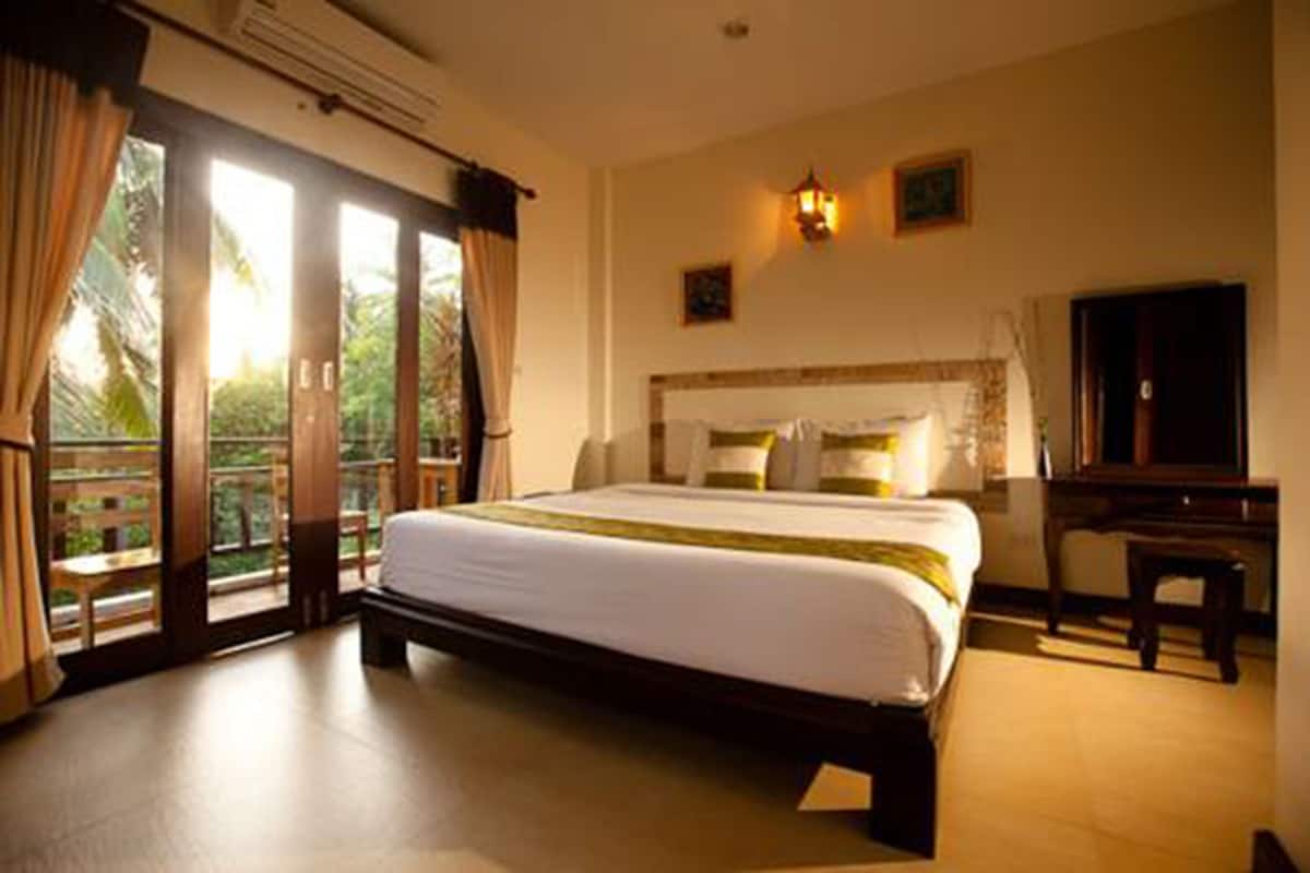 Ein Hotelzimmer mit einem großen Bett, einem Schreibtisch und Blick ins Freie durch eine Schiebetür.