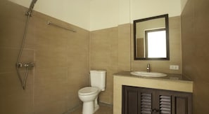 Un baño con inodoro, lavamanos, espejo y ducha.