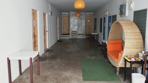 A hallway with a green rug, a wicker chair with orange cushions, and a hanging orange pendant light. - Tree Residences (Chiang Mai)