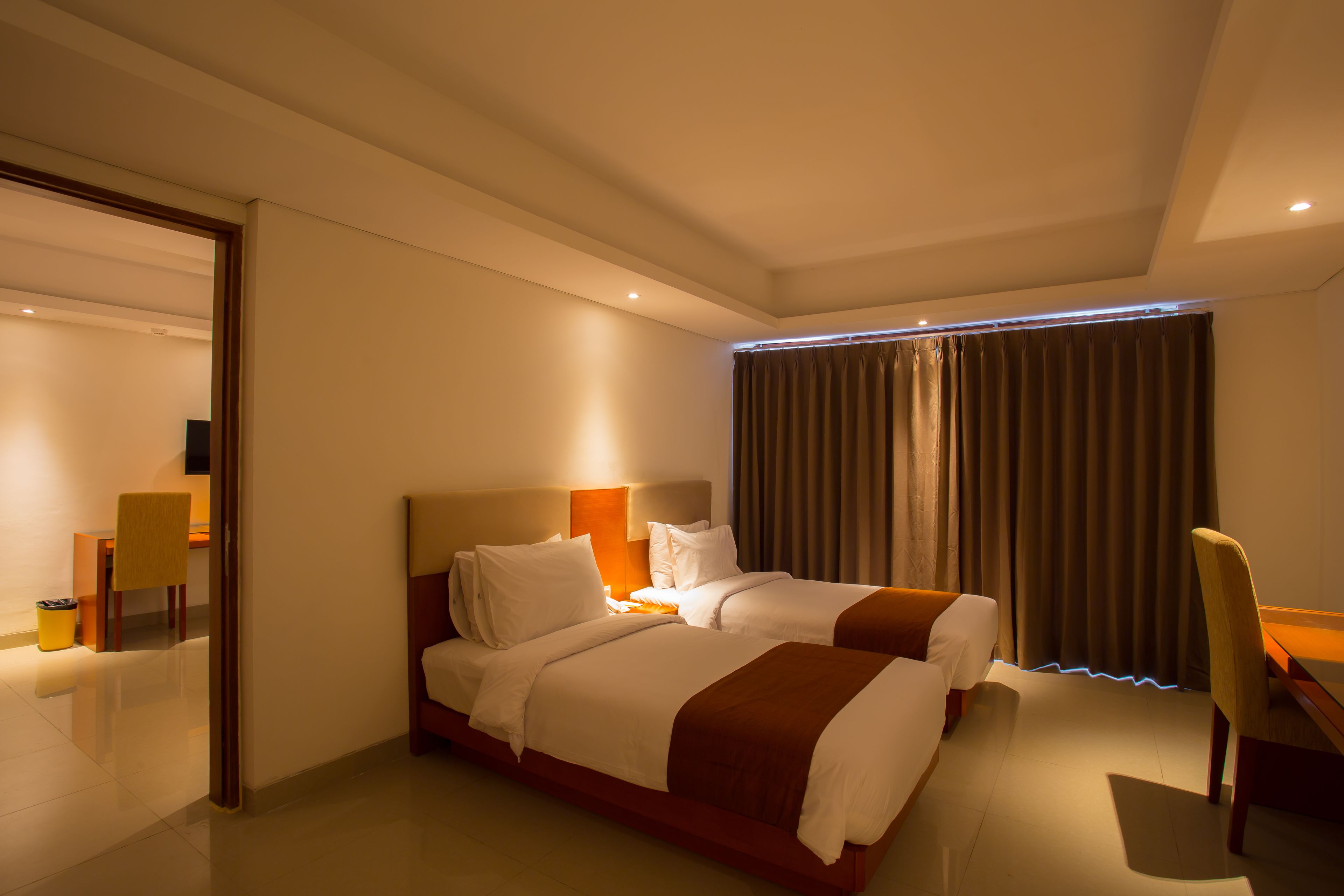A hotel room with two beds, a desk, and a chair.